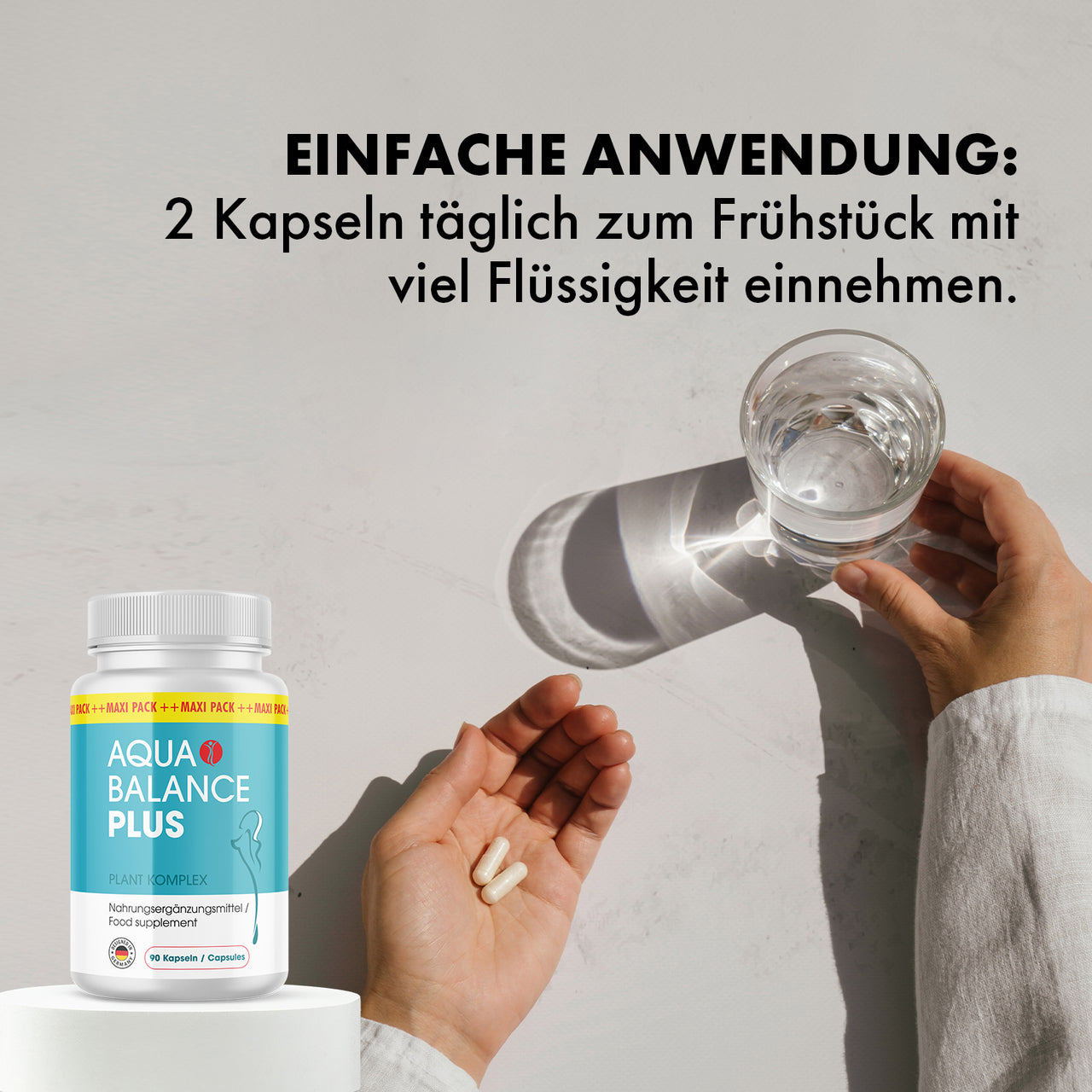 Hand mit zwei Kapseln und Glas Wasser, Nahrungsergänzung Aqua Balance Plus mit Anwendungshinweis