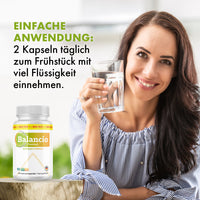Thumbnail for Frau hält Glas Wasser neben Balancio Premium Dose mit Anwendungshinweis 2 Kapseln täglich