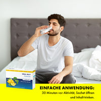 Thumbnail for Mann sitzt auf Bett und trinkt Wasser neben Oral Jelly Premium Verpackung mit Anwendungstext