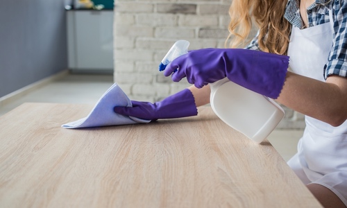 fettflecken entfernen holz arbeitsplatte gummihandschuhe lappen spray frau